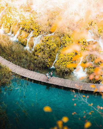 plitvice lake two person walking on boardwalk over body of water plitvice